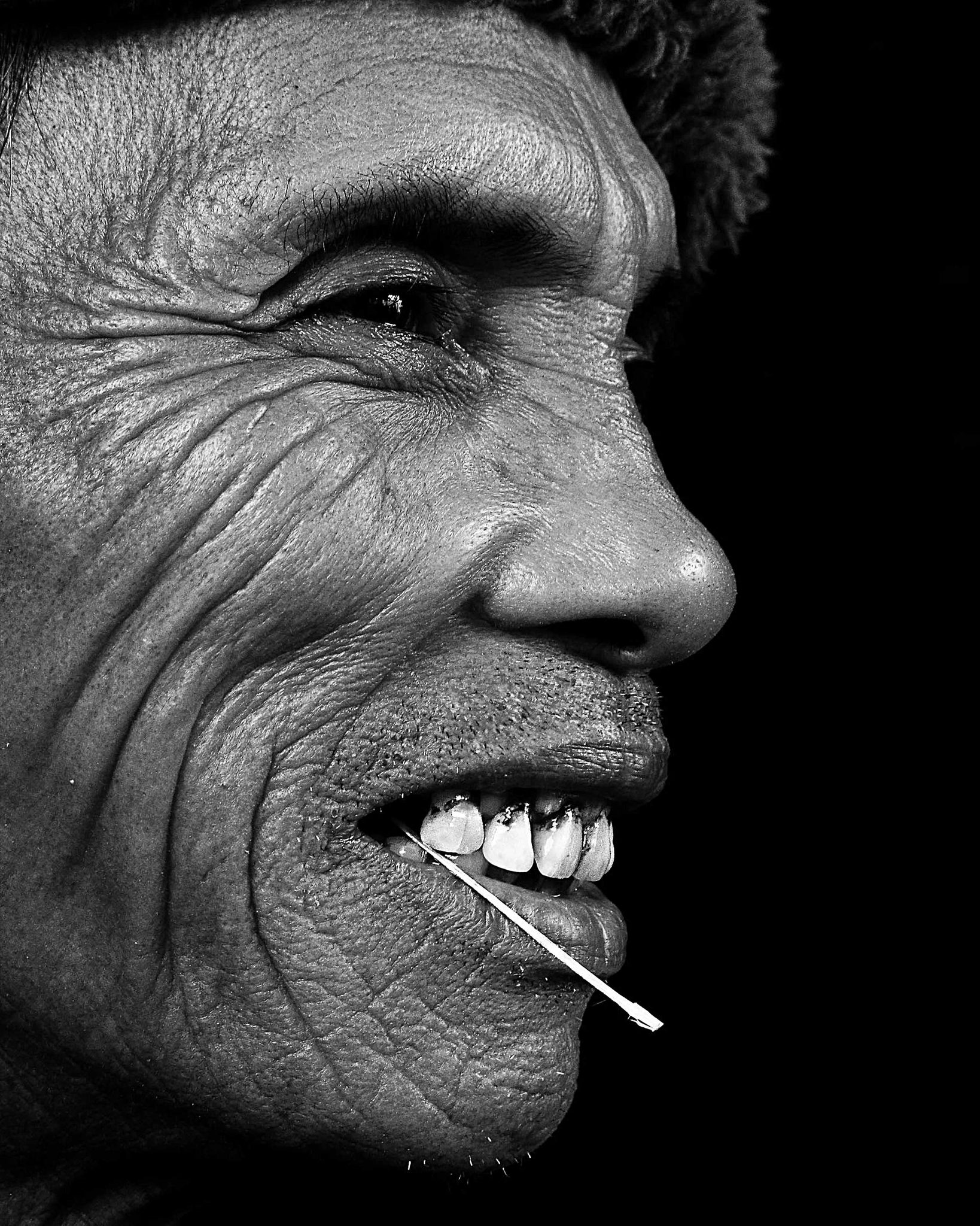 Man, toothpicj, teeth, smiling. Portrait photograph by Christopher Maxwell, finalist in the Shoot The Frame Portrait photography award, February 2015