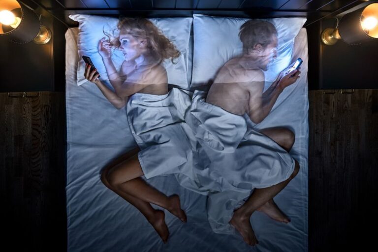 Couple, cellphone, bed. Portrait photograph by Al Lapkovsky, finalist in the Shoot The Frame Portrait photography award, April 2018
