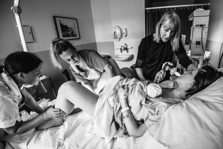 Giving birth, woman, midwife. Portrait photograph by John Nelson, finalist in the Shoot The Frame Portrait photography award, April 2018